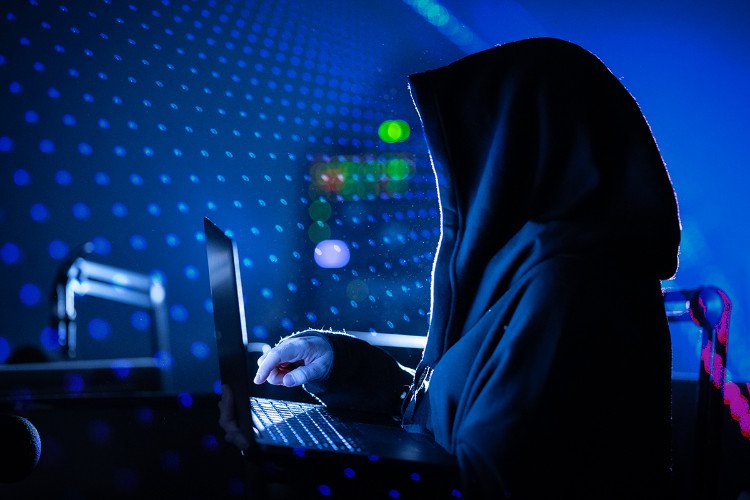 Изображение интернет-мошенника, который с помощью ноутбука пытается обмануть наивных пользователей сервиса «Госуслуги»
