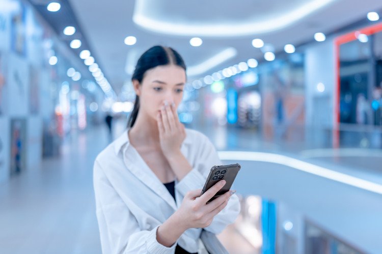 Стильная девушка с ужасом смотрит в свой гаджет - смартфон