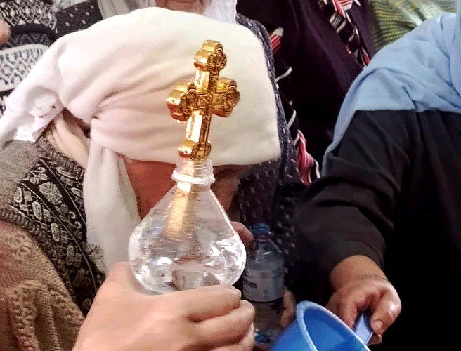 женщина держит крест на водосвятном молебне в Свято-Троицком храме Усть-Лабинска