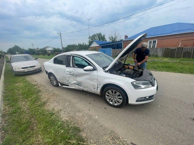 белый автомобиль Volkswagen Passat с помятой передней пассажирской дверью и открытым капотом, у которого стоит водитель