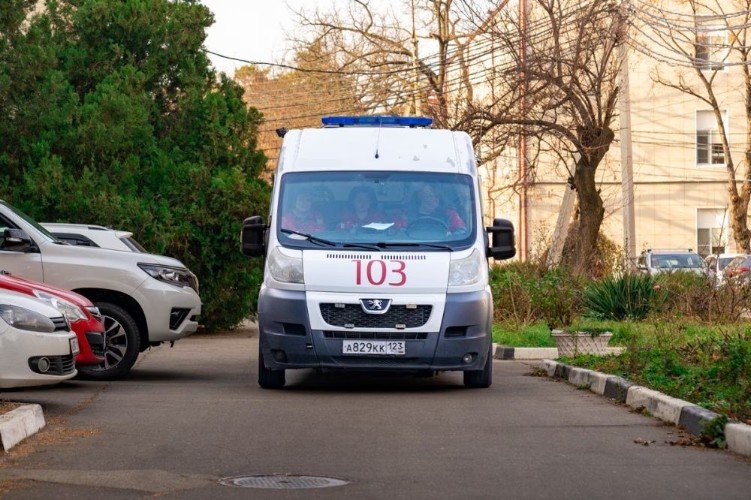 машина скорой помощи едет по дороге во дворе многоэтажек
