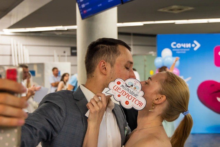 жених и невеста целуются в аэропорту Сочи