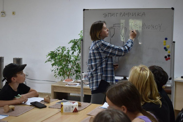 преподаватель пишет на маркерной доске греческие слова