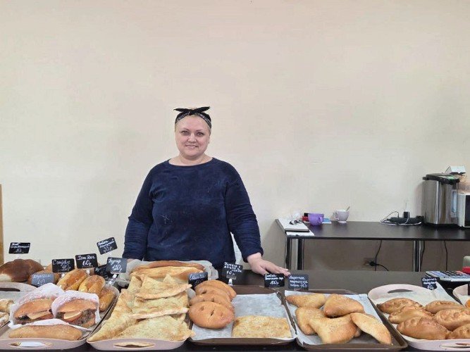 Светлана Мальцева стоит за столом с выпечкой