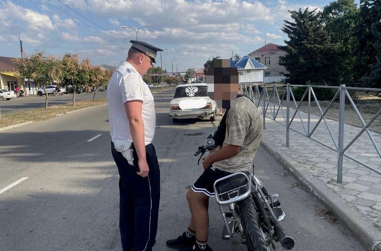 Госавтоинспектор разговаривает с подростком на скутере