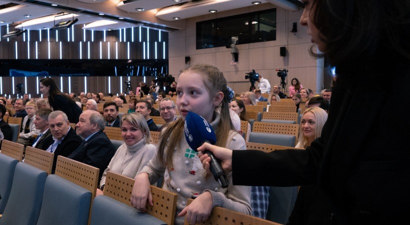 Зал с людьми и девочка с микрофоном