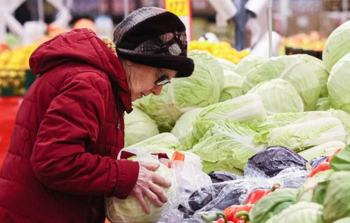 Женщина выбирает капусту на прилавке