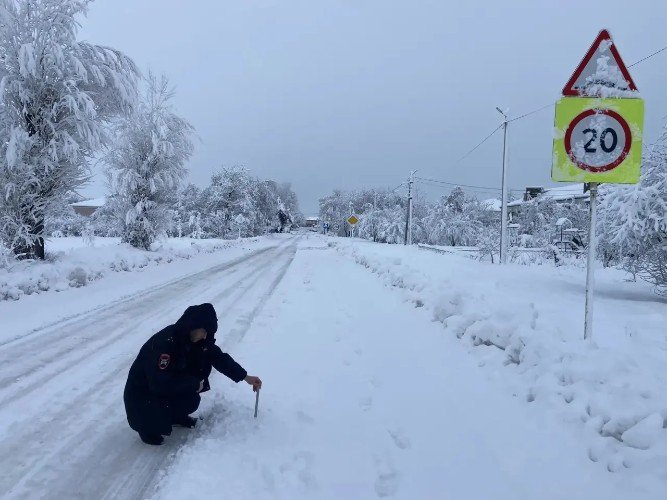 Сотрудник дорнадзора измерят высоту снежного покрова на дороге