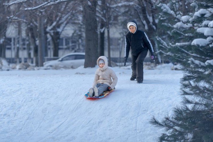 Ребёнок на ледянках катится с горки