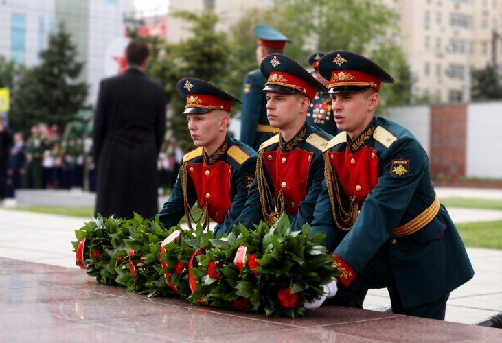 Молодые люди в форме возлагают цветы к памятнику