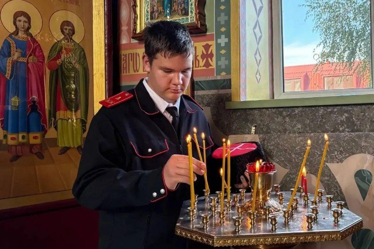 Кадет ставит свечу в храме