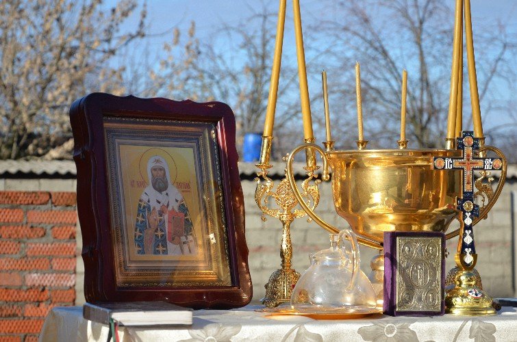 Икона святителя Патриарха Тихона, чаша и свечи на столе