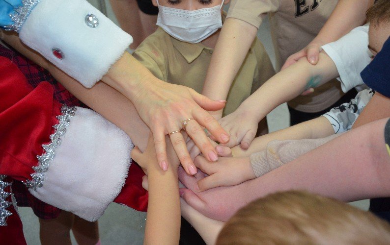 Руки детей на варежку Деда Мороза