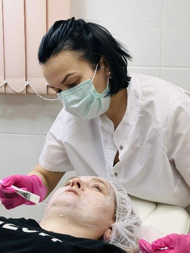 Эстетист Елена Зайченко наносит маску на лицо клиента