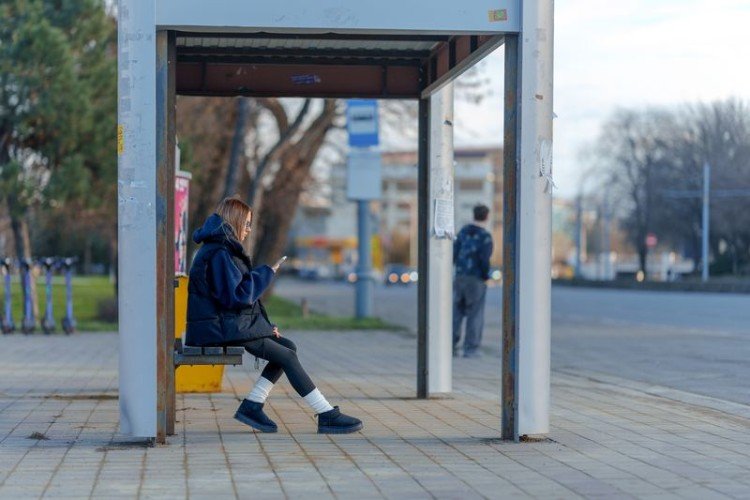 Девушка с телефоном на остановке