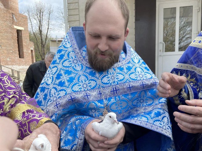 Отец Кирилл Карканов держит белого голубя