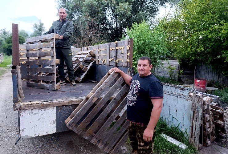 Мужчины разгружают деревянные палеты