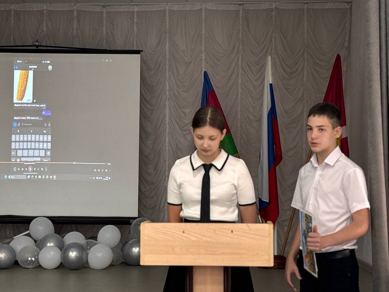 ученица и ученик защищают проект в школьном зале