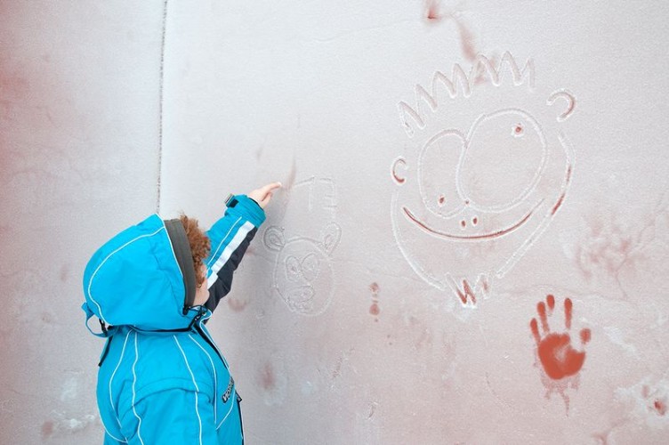Мальчик рисует на замёрзшей стене