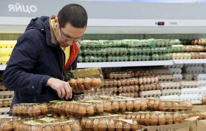 Мужчина выбирает яйца в магазине